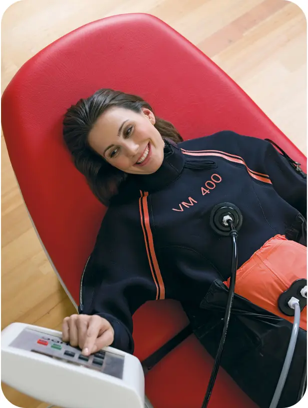 Stranka sproščeno leži in uporablja HYPOXI VM 400 sistem